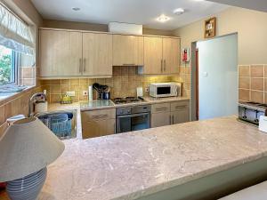 une cuisine avec des armoires en bois et un réfrigérateur blanc dans l'établissement Blossom's Cottage, à Albourne