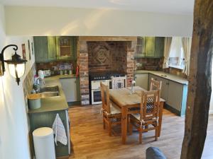Una cocina con gabinetes verdes y una mesa y sillas. en The Old Stables, en Bakewell
