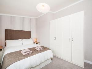 a bedroom with a large bed with white cabinets at Thistle Lodge in Auchterarder +9 photos