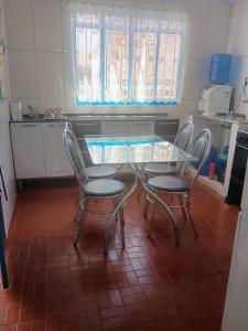 a kitchen with a glass table and two chairs at Pousada Nossa Senhora Da Polônia in Cachoeira Paulista