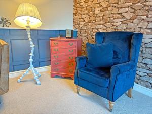 Waltham on the WoldsThe Stables的一把蓝色椅子，旁边是一盏灯和一个红色梳妆台。 更多10张照片