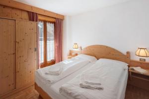 a bedroom with a white bed with two towels on it at Ciasa Lino Rotic in Pozza di Fassa +13 photos