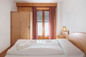 a bedroom with a white bed and a window at Ciasa Lino Rotic in Pozza di Fassa