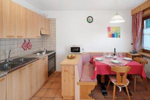 a kitchen with a table with a red table cloth on it at Ciasa Lino Rotic in Pozza di Fassa