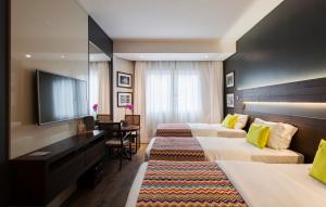 a hotel room with two beds and a flat screen tv at Hotel Cercano in Gramado +46 photos