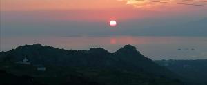 ein Sonnenuntergang, bei dem die Sonne über den Bergen untergeht in der Unterkunft YouGa Nest in Vívlos