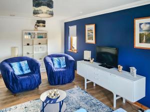 a living room with two blue chairs and a tv at Pine View in Cairisiadar