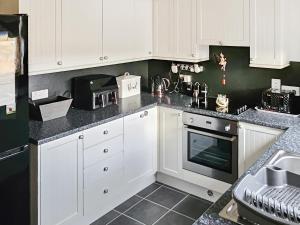 a kitchen with white cabinets and black counter tops at Pine View in Cairisiadar