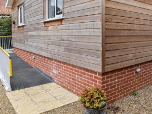 a house with a wooden wall and a brick wall at Chestnut Lodge in Old Buckenham