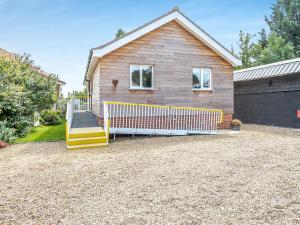 a house with a fence in front of a driveway at Chestnut Lodge in Old Buckenham +12 photos