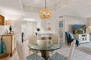 a dining room and kitchen with a glass table and chairs at Beach Club, Unit 134 in East End +10 photos