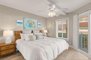 a bedroom with a large white bed with a ceiling fan at Beach Club, Unit 134 in East End