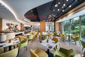 a restaurant with white tables and yellow chairs at Hyatt Place Dhaka Uttara in Dhaka