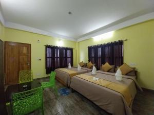 two beds in a room with yellow walls and windows at Rupsadeya Homestay in Mangpu