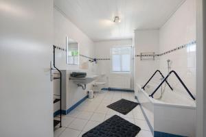 a white bathroom with a tub and a sink at Ferienhaus Neumann in Heide +32 photos