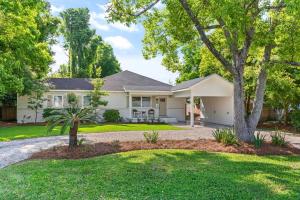 a white house with a tree in the front yard at Getaway Cottage - 615 Bartow St in Saint Simons Island