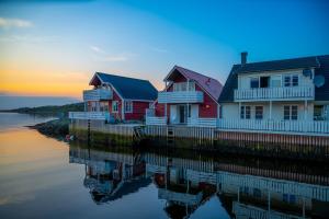 een rij huizen op het water bij zonsondergang bij Eldur Seaside Cabin in Stavang