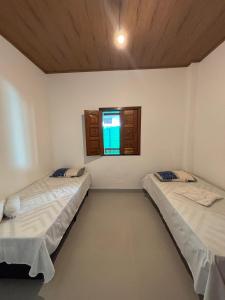 Dos camas en una habitación con ventana. en Flor de Lótus - Ilha de Boipeba, en Isla de Boipeba
