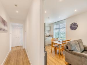 a living room and dining room with a table and a clock at Levans Cottage in Lindale