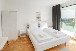 a white bedroom with a white bed and a window at Danube Suites in Vienna