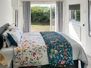 a bed with a flowered blanket on it with a window at Revita in Egremont +9 photos