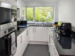 a kitchen with white cabinets and a sink and a window at Revita in Egremont