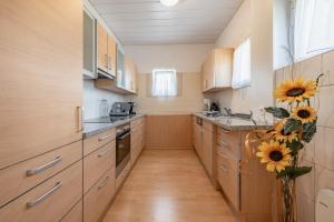 a kitchen with wooden cabinets and a vase of sunflowers at Landhof Unterkreuter in Zwickenberg +17 photos