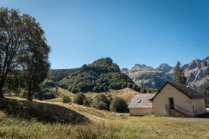 a house in a field with mountains in the background at Chalet Confortable 14 voyageurs in Urdos