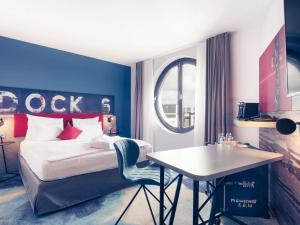 a bedroom with a bed and a table and a desk at Mercure Hotel Hamburg City in Hamburg