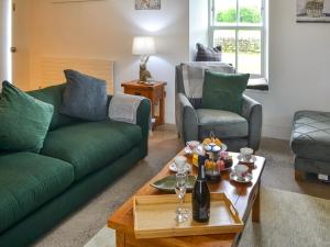 een woonkamer met een groene bank en een tafel bij The Haining in Elsdon