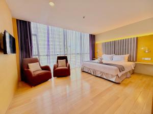 a hotel room with a bed and two chairs at NuEmpire Subang Suite - Empire Hotel in Subang Jaya