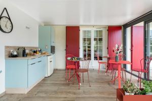 a kitchen and dining room with red chairs and a table at La Clé des Chaumes - Chambre d'hôte, Bed and Breakfast avec piscine et bain nordique in Boisset-lès-Montrond