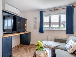 a living room with a couch and a tv at The May Tree in South Creake