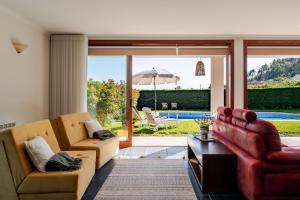 - un salon avec deux canapés et un parasol dans l'établissement Quinta do Outeirinho - Villa Deluxe, à Celorico de Basto
