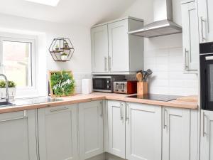 une cuisine avec des armoires blanches et un comptoir dans l'établissement The Barn, à Llangwm