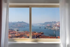 a window with a view of the water and buildings at Vegan Topfloor - Douro e Ribeira in Bandeira