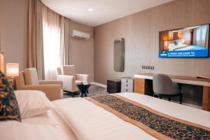 Una habitación de hotel con una cama y un televisor en la pared. en Swiss International Rancho Valeria, Warri, en Warri