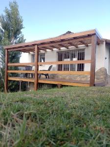 ビージャ・ヒアルディノにあるCasa de huéspedes con pileta.の家の前に椅子が2脚置かれた木製のパーゴラ