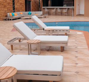 un groupe de chaises longues et une piscine dans l'établissement Swiss International Rancho Valeria, Warri, à Warri