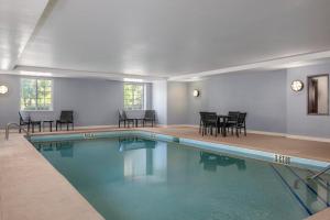 a swimming pool with chairs and tables in a building at Candlewood Suites Mooresville Lake Norman,NC by IHG in Mooresville