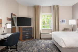 a hotel room with a bed and a desk and a television at Candlewood Suites Mooresville Lake Norman,NC by IHG in Mooresville