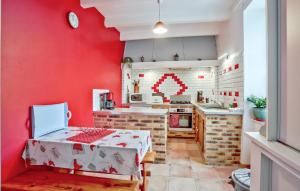 a kitchen with red walls and a table in a room at 3 Bedroom Amazing Home In Vergoncey in La Croix-Avranchin