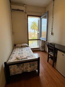 a bedroom with a bed and a desk and a window at Plaza Hotel Fray Bentos in Fray Bentos