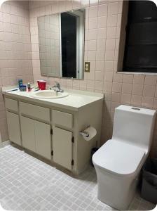 a bathroom with a toilet and a sink and a mirror at Happy Vacation in Largo