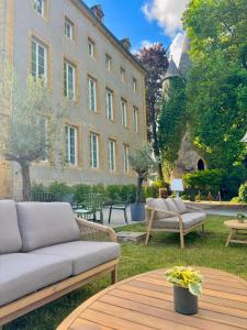a patio with a couch and tables in front of a building at Hôtel Château Schengen in Schengen