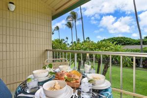 a table with bowls and plates of food on a balcony at Napili Shores F246 · NS F246 Spacious Condo w Pools AC Near Napi in Kahana