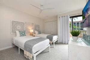 a bedroom with two beds and a tv and a window at Maui Kamaole E202 · MKO E202 Remodeled 2BD Retreat wAC Pool Near in Wailea +59 photos