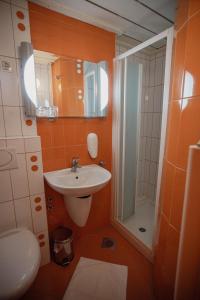 an orange bathroom with a sink and a shower at MC Hotel in Žalec +52 photos