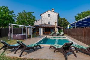a backyard with a pool and chairs and a house at Villa Histria, a wonderful and luxurious villa in Manjadvorci +28 photos