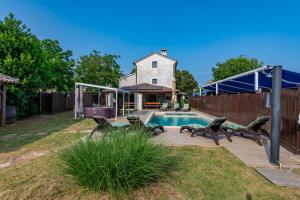 a backyard with a pool with chairs and a house at Villa Histria, a wonderful and luxurious villa in Manjadvorci